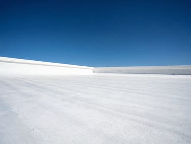 Low-angle architectural shot of a clean white TPO roof membrane under brilliant Phoenix sun, crisp shadows, deep blue sky
