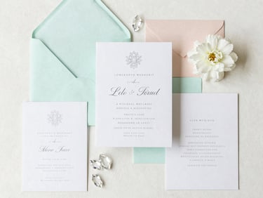 A beautifully styled wedding registry flat-lay with elegant invitation suites, fine crystal, and pastel mint accent details, soft daylight
