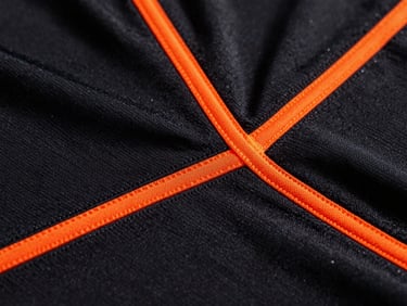 Close-up of high-performance soccer jersey fabric texture, sharp orange seams, dramatic dark studio lighting