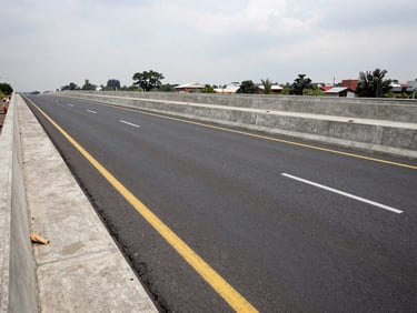 Wide panoramic shot of completed urban road infrastructure in Mexico City, concrete and asphalt surface with lane markings, overcast daylight, no people, documentary infrastructure photography