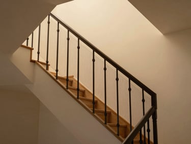 Interior staircase of a house with a fine protective net installed along the open side of the banister, warm ambient light, clean modern interior