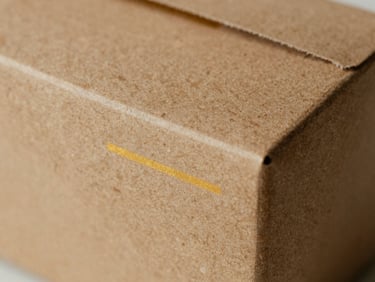 Macro close-up of a structured saffron paper box with clean gold foil-stamping detail, soft side-light.