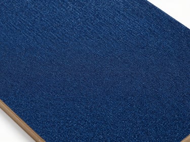 Macro-texture photograph of a deep indigo denim-fiber composite panel surface, crisp studio lighting, architectural sample
