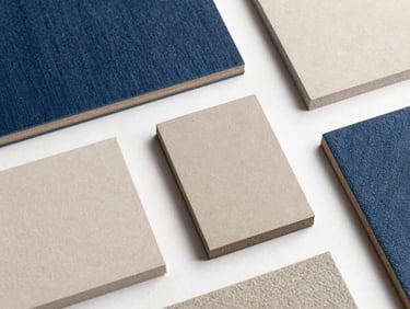 Clean flat-lay of custom architectural material samples in beige, charcoal, and denim blue, natural daylight, architectural design studio