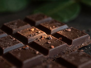 Artisanal dark chocolate bars with visible cocoa nibs, rustic texture, warm highlights, side-lit.