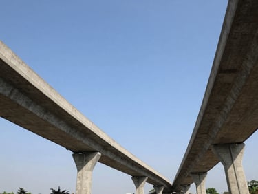 Wide-angle architectural photograph of a massive concrete highway flyover in India, sweeping curves, clear blue sky, bright daylight, monumental scale