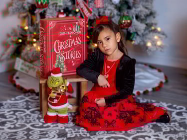 a little girl sitting on a chair with a book and a griner