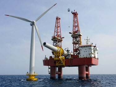 A heavy-lift jack-up vessel standing on legs in the ocean, installing a massive offshore wind turbine generator.