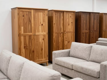 A bright, clean showroom in Dubai International City displaying well-maintained used wooden wardrobes and neat fabric sofas, natural daylight.