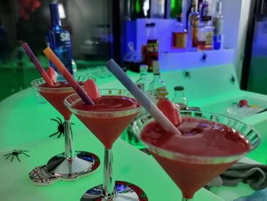 Cocktail glasses filled with slushy on the glow bar with accessories at a halloween event, Redlands.