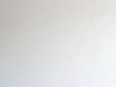 Close-up of a newly repaired drywall section, perfectly smooth and blended into the existing wall, ready for paint.