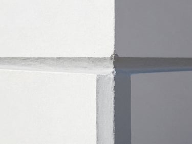 Close-up of a perfectly painted interior wall corner, showing crisp, straight lines where two colors meet, natural coastal daylight.