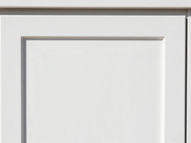 Close-up of a newly refinished cabinet door, showing a flawless, glossy white surface with no brush strokes, under bright light.
