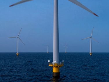 Wide-angle view of offshore wind turbines standing in deep ocean waters, cool blue glow of dusk, technical marine sensors mounted on the turbine base.