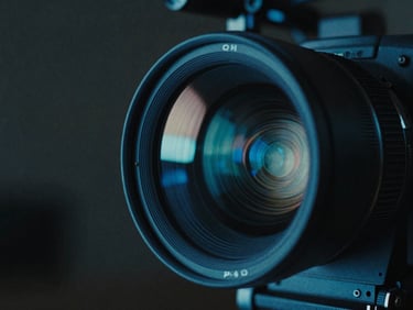 Cinematic close-up of an anamorphic camera lens reflecting cold blue neon lights, dark film set background, moody chiaroscuro lighting.