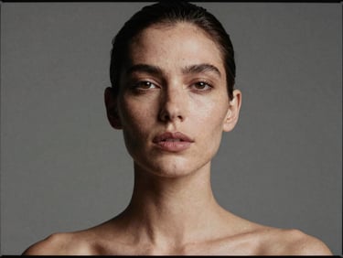 Editorial studio headshot of a female model with natural expression, high contrast lighting, neutral background, medium format film.