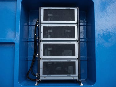 Sharp industrial photography of a marine-grade server rack installation inside a vessel, crisp cool LED lighting, deep blue and metallic tones, high-contrast architectural framing of cables and technical equipment.