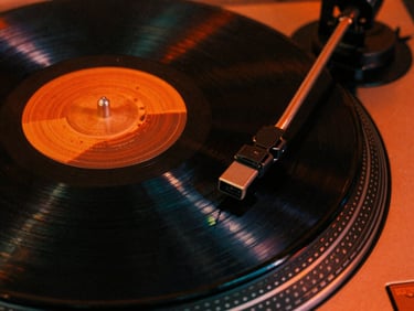Extreme close-up of a spinning vinyl record on a vintage turntable, neon orange rim light, deep shadows, 35mm grain, high contrast