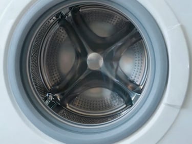 Close-up of a clean washing machine drum with metallic silver accents, crisp daylight.