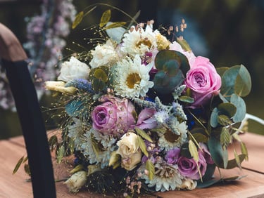 Bunter Brautstrauß mit Rosen und Eukalyptus auf einem Holzstuhl. Hochzeitsfloristik-Foto: Just Perspectives.