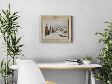 Framed winter landscape painting on a white wall above a modern desk with green plants.
