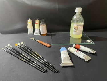 Professional oil painting supplies including brushes, paint tubes, and solvent on a black studio surface.