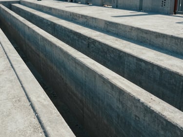 Wide-angle environmental shot of a newly constructed concrete municipal drainage channel, sharp architectural lines, natural daylight, desaturated blue tones, 35mm