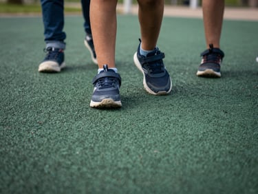 Low-angle close-up of textured forest green rubber playground surface, children's sneakers dynamically landing, soft natural daylight, showing true color depth.