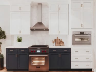 Modern luxury kitchen featuring white upper cabinets, navy blue lower cabinets, and a stainless steel Wolf range.