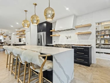Modern luxury kitchen featuring a marble waterfall island with faux fur stools and gold pendant lights.