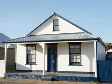 Wide environmental shot of a restored heritage cottage in Perth, freshly painted in crisp navy and white, glowing under bright afternoon sunlight, 35mm.