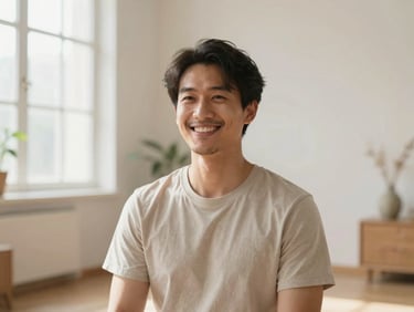 Portrait of a male yoga instructor in a bright, minimalist room, smiling warmly, soft daylight, natural home environment.