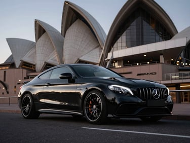Low-angle wide shot of a sleek black Mercedes-AMG C63 S coupe parked against a modern Sydney architectural backdrop at twilight, sharp contrast, high-end commercial style, 35mm lens.