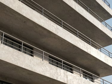 Geometric close-up of DLF Aralias luxury balconies, showcasing clean concrete lines and steel railings in crisp sunlight.