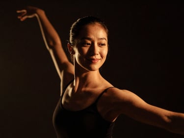 Low-key dramatic portrait of a female dancer, warm lighting, gentle smile, rich contrast, 35mm film.