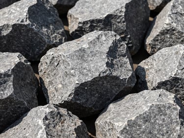 Sharp close-up of heavy ballast stones, large angular grey rocks for railway support.