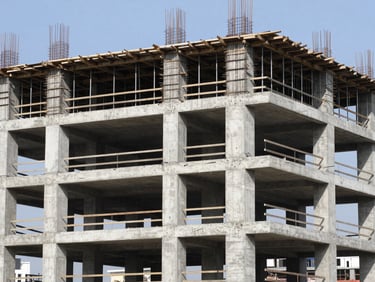 Industrial documentary photo of a modern multi-story residential concrete structure under construction, raw concrete pillars, bright midday sun, sharp focus, 35mm lens.