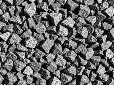 Close-up of crushed grey granite gravel, sharp angular edges, high contrast texture.