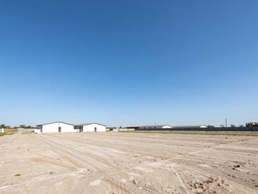 Well-framed wide-angle shot of a clean development land lot under a clear blue sky, professional real estate photography