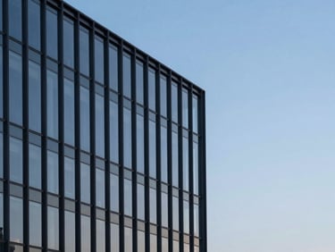 Modern glass and steel building facade reflecting a cool blue morning sky, minimalist architectural photography