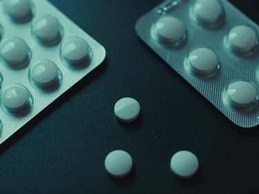 Overhead view of clinical tablets and medicine packaging on a dark reflective surface, clinical green lighting