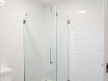 Bright, high-key daylight photograph of a completed modern bathroom renovation with crisp white subway tile, clean grout lines, and a glass door.
