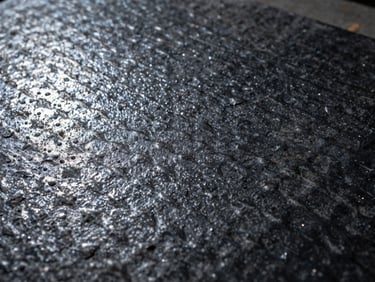 Close-up of textured sand-grain black powder coated steel plate, rugged industrial surface
