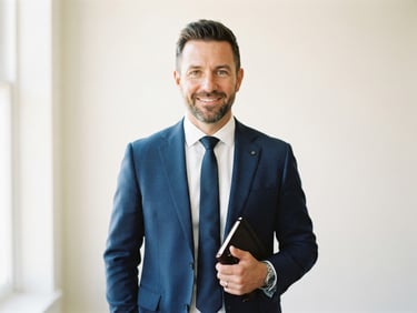 Crisp editorial portrait of a professional male instructor in a navy suit, bright natural daylight, clean cream background.