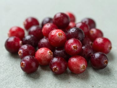 Macro shot of fresh cranberries on a textured surface, vibrant red color, soft natural daylight, shallow depth of field.