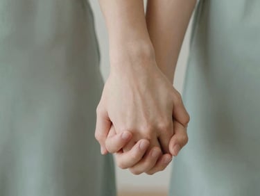 Close-up of a couple's hands gently intertwined, soft focus, warm lighting, conveying intimacy and connection, natural daylight.