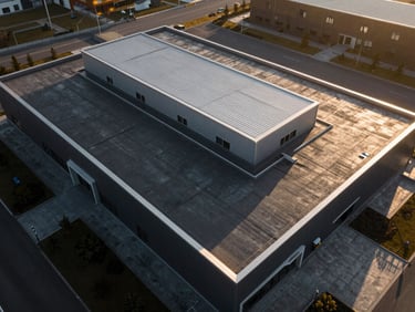 Top-down geometric drone shot of a modern commercial flat roof with clean lines and silver metal flashing