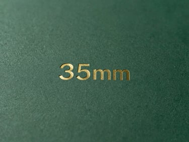 Close-up of tactile print materials with subtle branding, soft natural daylight, deep forest green and gold accents, clean minimalist composition, 35mm