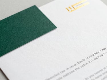 Elegant close-up of a business card and letterhead design, gold foil accents, soft natural light