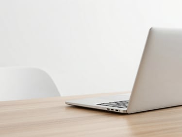 Open modern metallic laptop on a clean wooden desk, minimalist workspace, soft overcast light